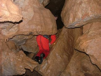 Caver squeezes through a tight gap in a pothole