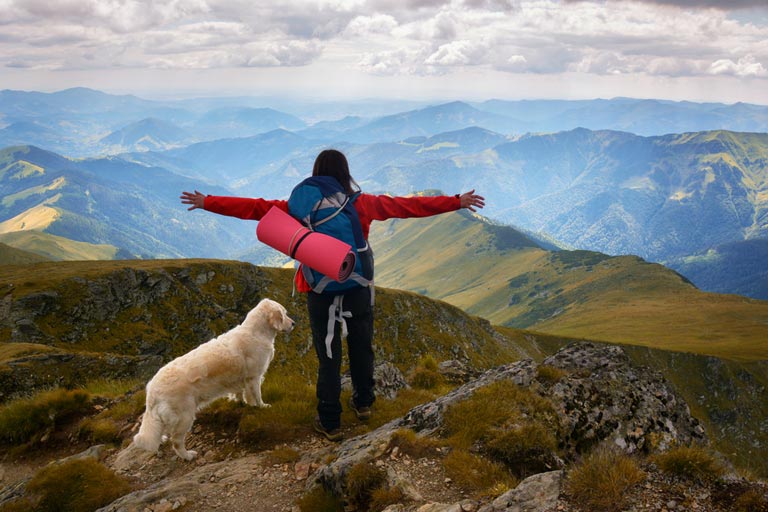 Woman and Dog standing on top of a mountain