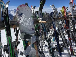 skis and snowboards on a rack while skiers dine at mountaintop restaurant